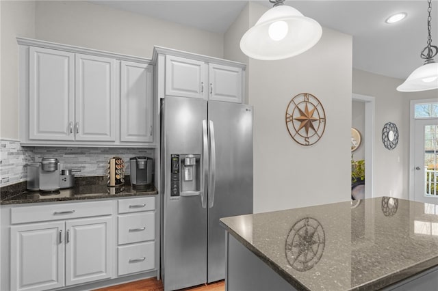 kitchen featuring stainless steel fridge with ice dispenser, white cabinetry, and dark stone countertops