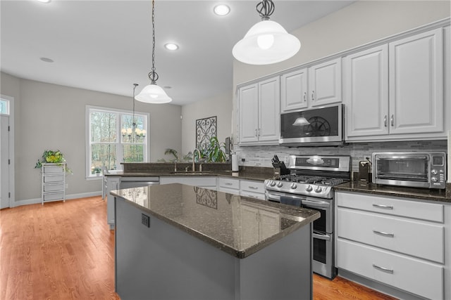 kitchen with decorative light fixtures, stainless steel appliances, and light hardwood / wood-style flooring