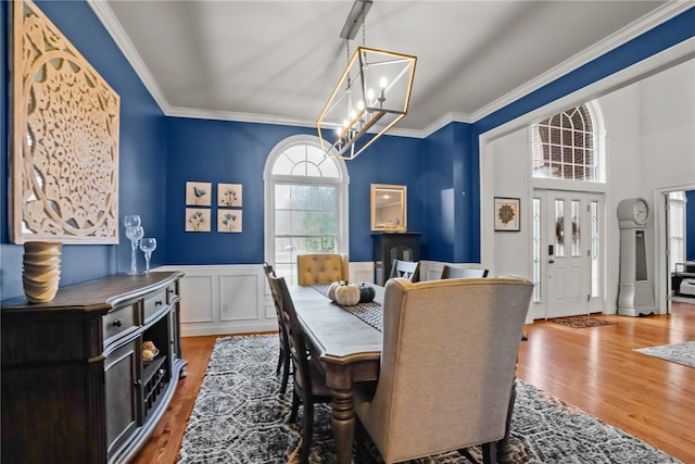 dining space with hardwood / wood-style flooring, crown molding, and a chandelier