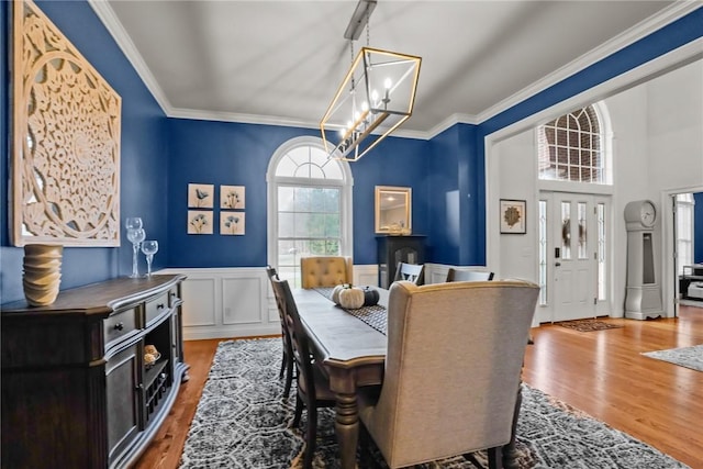 dining space with an inviting chandelier, wood-type flooring, and ornamental molding