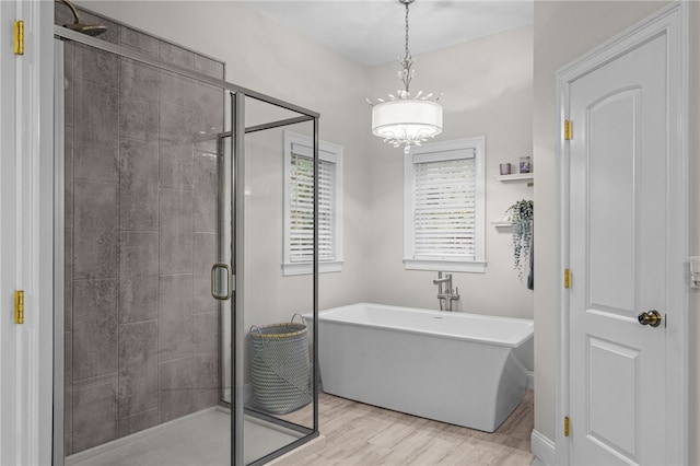 bathroom featuring an inviting chandelier, shower with separate bathtub, and hardwood / wood-style flooring