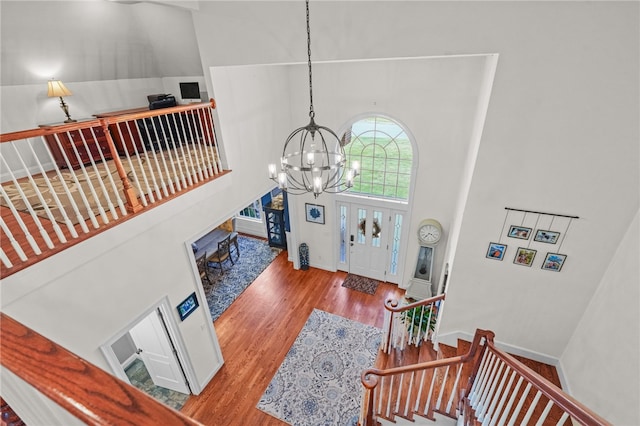 entryway featuring wood-type flooring, a high ceiling, and an inviting chandelier