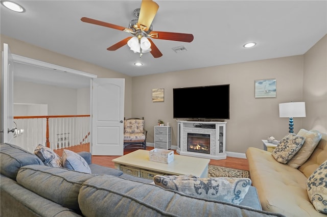 living room featuring hardwood / wood-style flooring, ceiling fan, and a fireplace