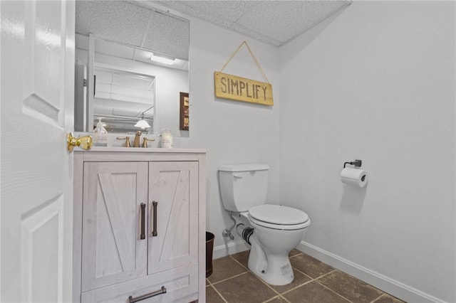 bathroom featuring tile patterned flooring, vanity, a paneled ceiling, and toilet