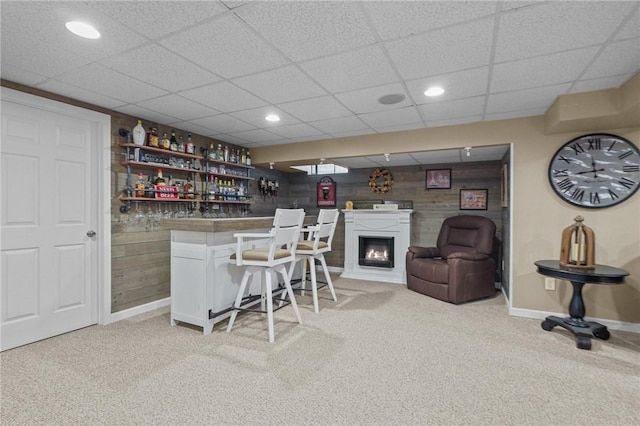 bar with wood walls, light carpet, and white cabinets