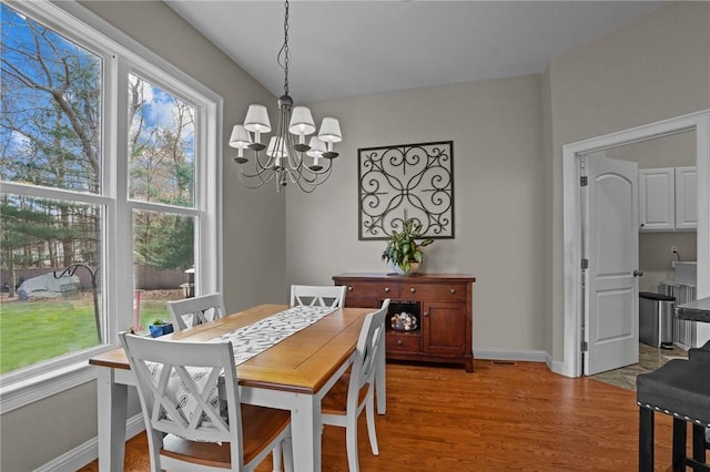 dining area with a wealth of natural light, a notable chandelier, and light wood-type flooring