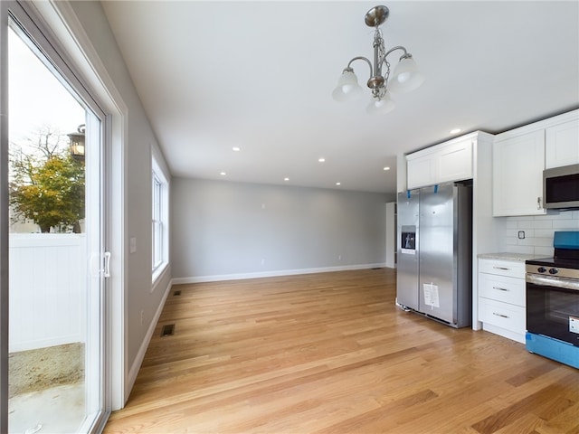 kitchen featuring white cabinets, decorative backsplash, light hardwood / wood-style floors, and appliances with stainless steel finishes