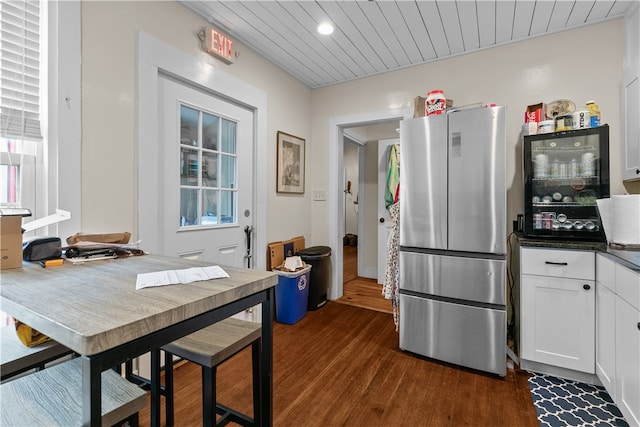 kitchen with white cabinets, stainless steel fridge, dark hardwood / wood-style flooring, and wooden ceiling