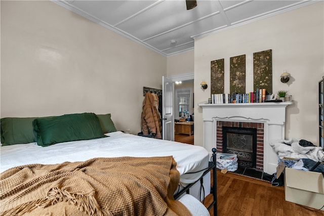 bedroom featuring dark hardwood / wood-style floors, ceiling fan, crown molding, and a fireplace