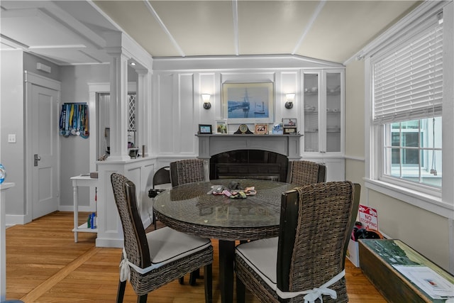 dining space with ornate columns, wood-type flooring, and lofted ceiling