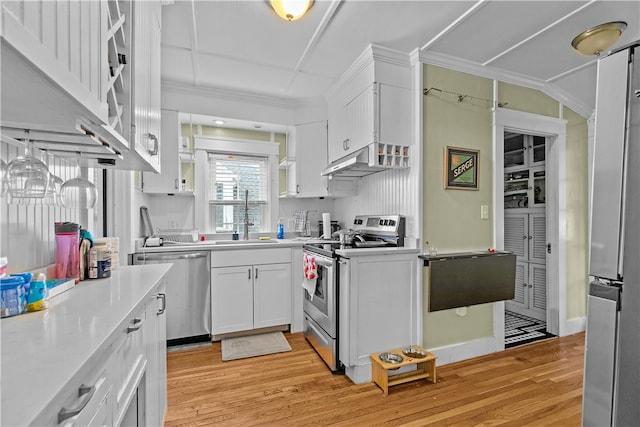 kitchen featuring sink, light hardwood / wood-style flooring, ornamental molding, white cabinetry, and stainless steel appliances