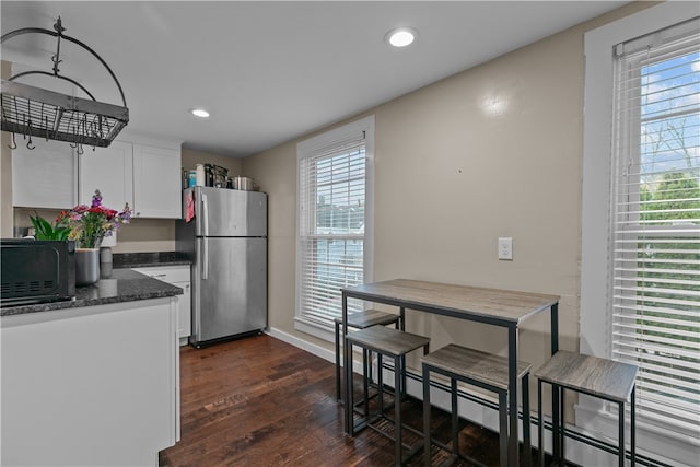 kitchen with stainless steel refrigerator, white cabinetry, dark hardwood / wood-style flooring, and a healthy amount of sunlight