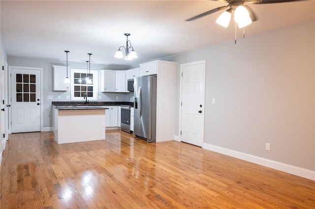 kitchen with white cabinetry, stainless steel appliances, pendant lighting, a kitchen island, and light wood-type flooring