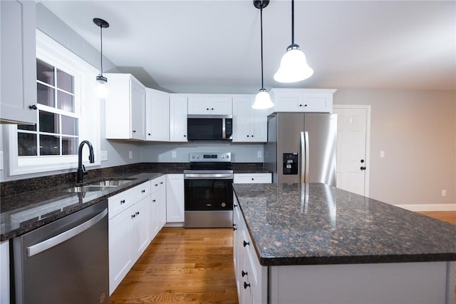 kitchen featuring appliances with stainless steel finishes, decorative light fixtures, and white cabinetry