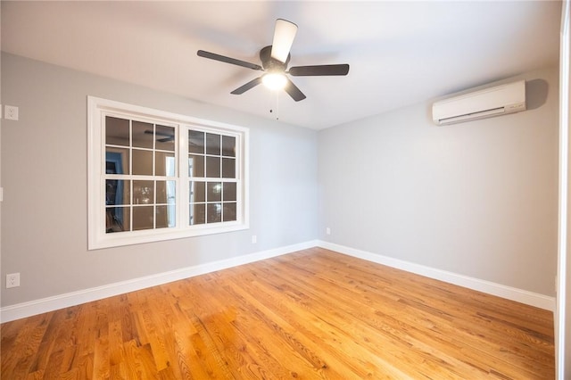 empty room featuring ceiling fan, light hardwood / wood-style floors, and a wall mounted air conditioner