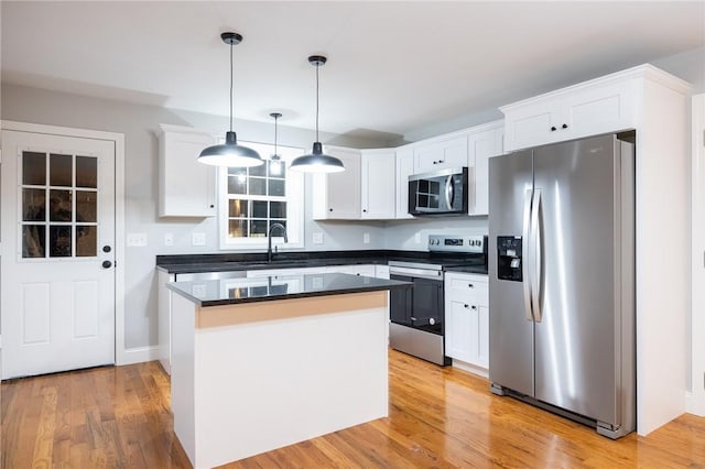 kitchen with pendant lighting, light wood-type flooring, stainless steel appliances, and white cabinetry