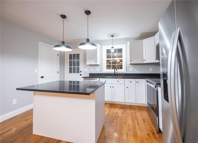 kitchen with white cabinets, light wood-type flooring, a center island, and stainless steel appliances