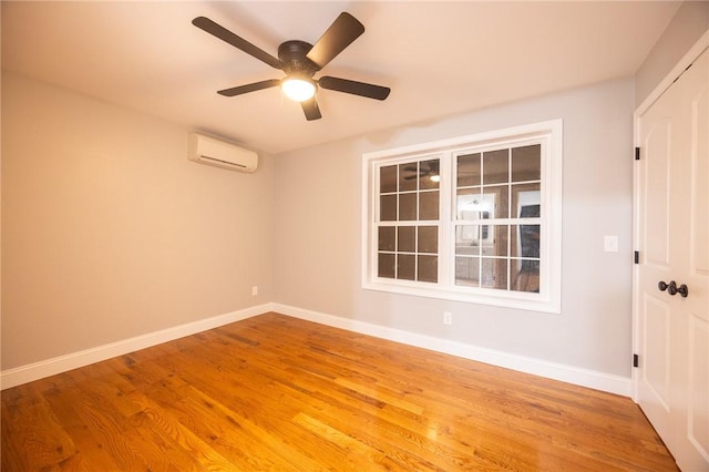 unfurnished room with light hardwood / wood-style floors, an AC wall unit, and ceiling fan