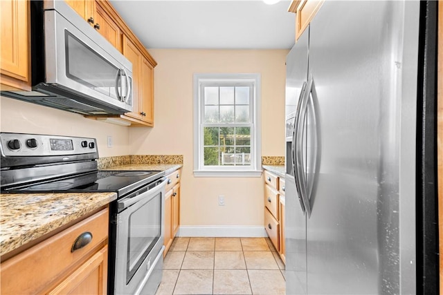 kitchen featuring light stone countertops, stainless steel appliances, and light tile patterned flooring