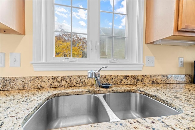 details featuring light stone countertops, light brown cabinetry, and sink