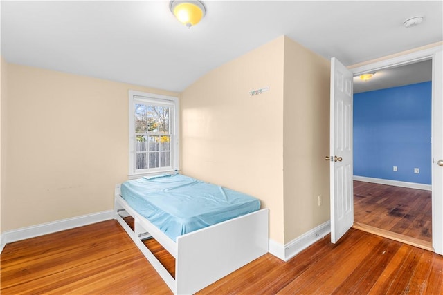 bedroom with vaulted ceiling and hardwood / wood-style flooring