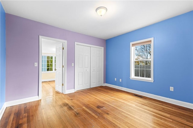 unfurnished bedroom with multiple windows, a closet, and wood-type flooring