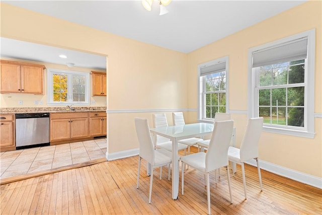 dining area featuring a healthy amount of sunlight, sink, and light hardwood / wood-style flooring