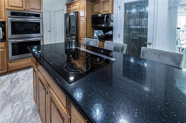 kitchen featuring black appliances, decorative backsplash, and dark stone countertops