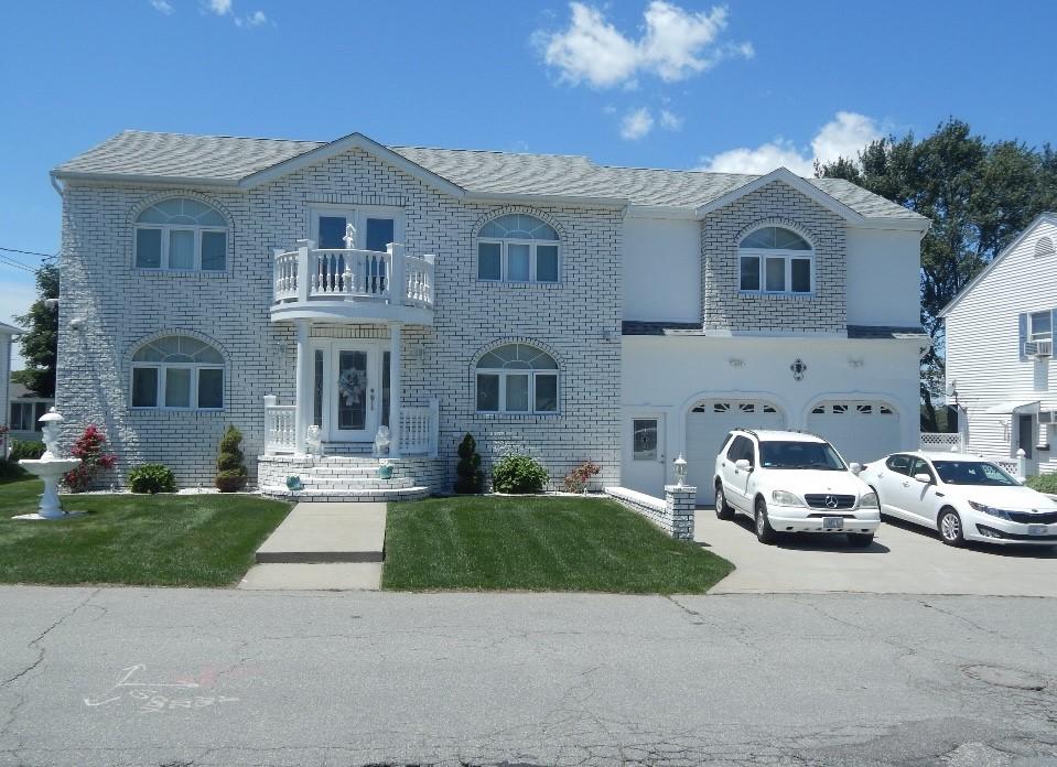 view of front facade with a balcony, a front lawn, and a garage