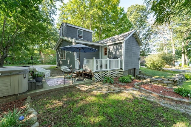 rear view of house featuring a lawn, a patio, a wooden deck, and a hot tub