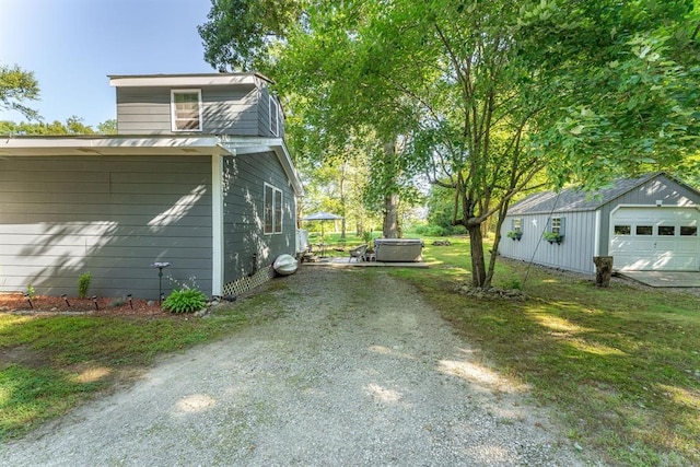 view of property exterior featuring a lawn, central air condition unit, a jacuzzi, an outbuilding, and a garage