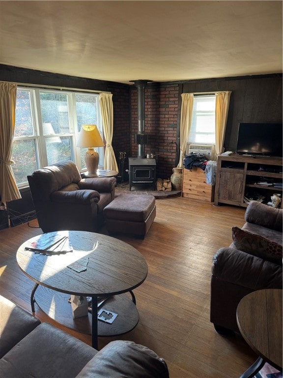 living room featuring wood-type flooring, a wood stove, and cooling unit