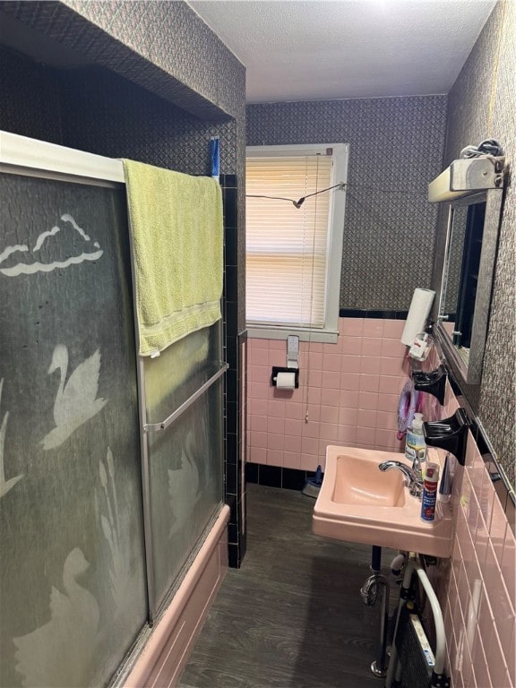 bathroom featuring hardwood / wood-style floors, sink, shower / bath combination with glass door, and tile walls