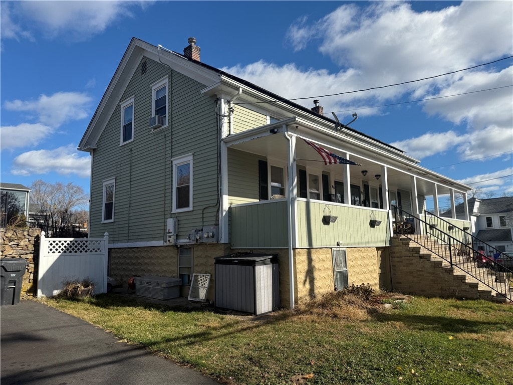 view of side of home with a porch, cooling unit, and a yard