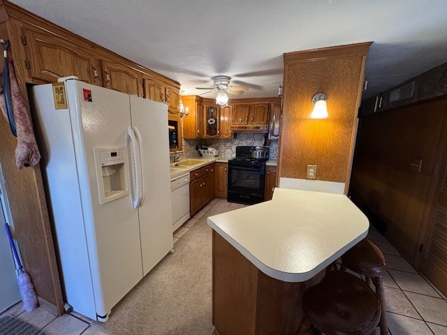 kitchen with white appliances, backsplash, ceiling fan, light tile patterned floors, and a kitchen bar