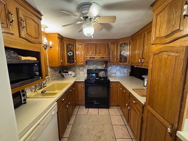 kitchen featuring decorative backsplash, white dishwasher, sink, light tile patterned floors, and black range