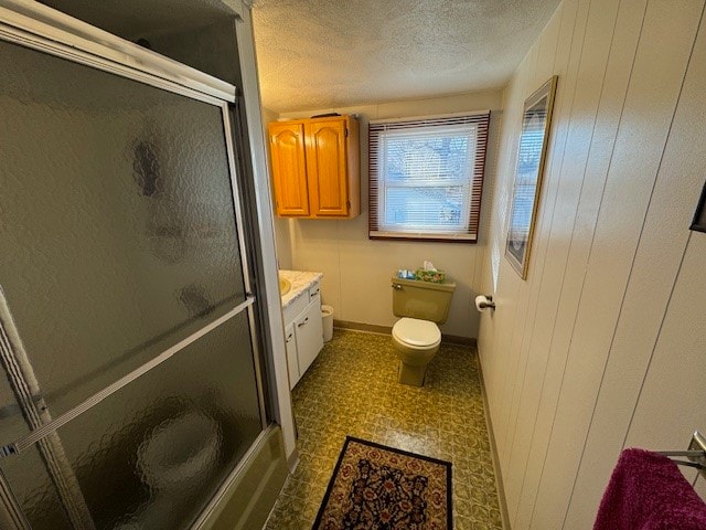 bathroom featuring vanity, wood walls, toilet, and walk in shower