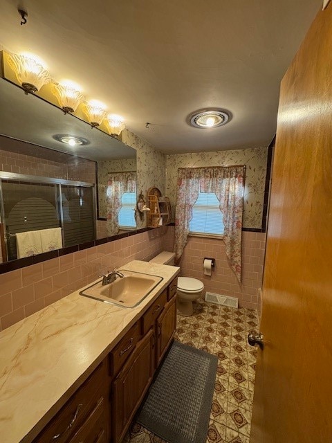 bathroom featuring vanity, an enclosed shower, and toilet