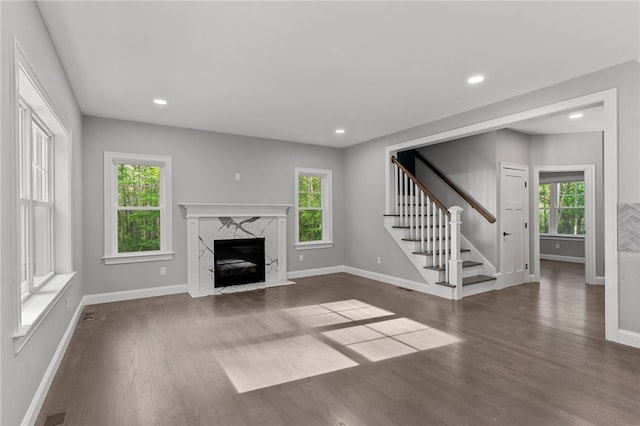 unfurnished living room featuring a high end fireplace and dark hardwood / wood-style flooring