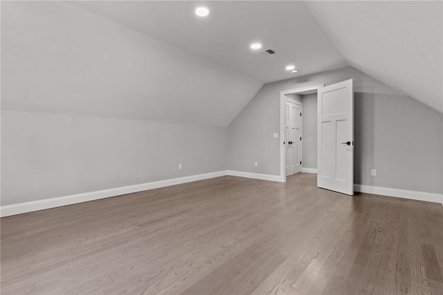 additional living space with wood-type flooring and vaulted ceiling