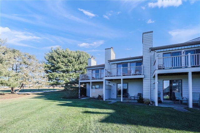 rear view of house with a yard and a balcony