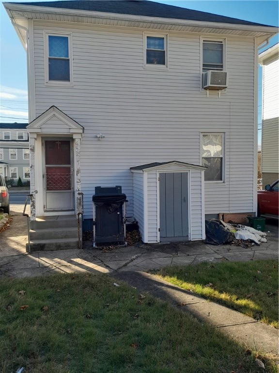 rear view of property featuring a lawn, cooling unit, and a storage shed