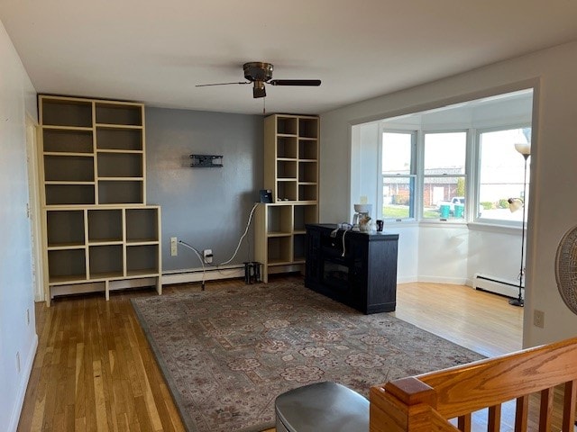 office space featuring wood-type flooring, ceiling fan, and a baseboard heating unit