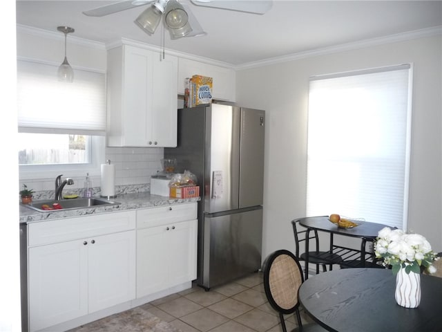 kitchen with decorative backsplash, white cabinetry, sink, and stainless steel refrigerator