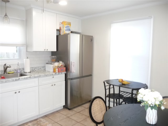 kitchen featuring stainless steel fridge, white cabinetry, hanging light fixtures, and sink