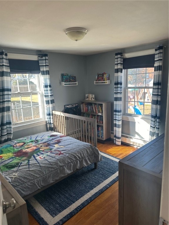 bedroom featuring baseboard heating and hardwood / wood-style floors