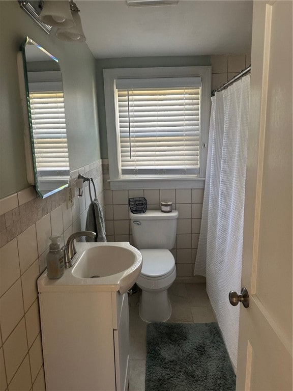 bathroom featuring tile patterned flooring, vanity, tile walls, and toilet