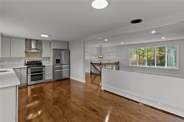 kitchen featuring wall chimney range hood, dark hardwood / wood-style flooring, a baseboard heating unit, gray cabinets, and appliances with stainless steel finishes