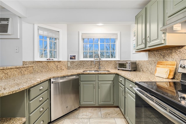 kitchen with green cabinets, sink, a healthy amount of sunlight, light stone counters, and stainless steel appliances