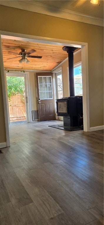 unfurnished living room featuring wood-type flooring, a wood stove, a wealth of natural light, and wooden ceiling